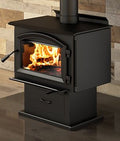 Black wood stove with flames inside, set against a wooden wall.
